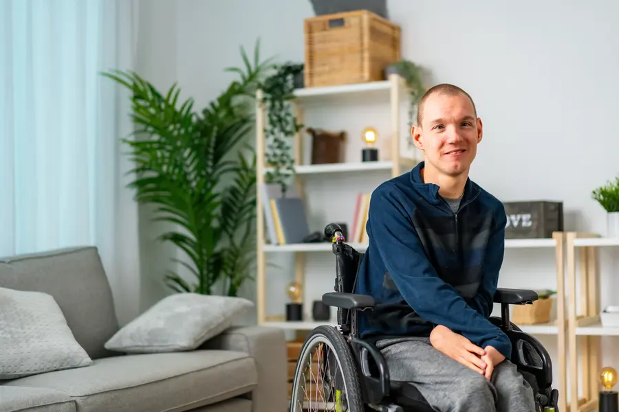 Young man in wheelchair looking candidly at the camera from his living room