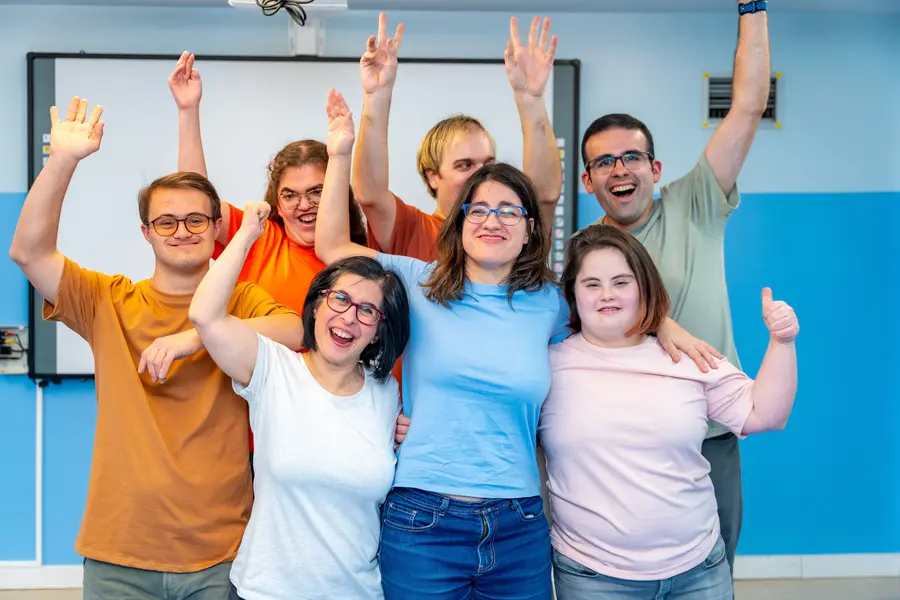Group of young adults with Down syndrome waving their hands in the air after enjoying a group fitness class together