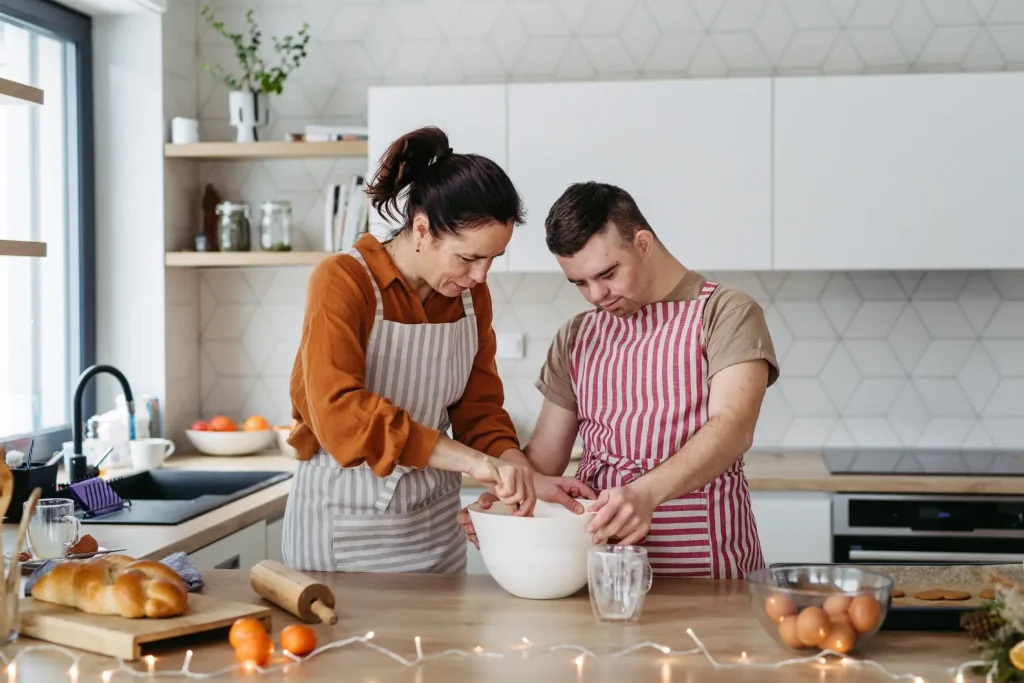 young man with Down syndrome baking bread in the kitchen with his female support worker