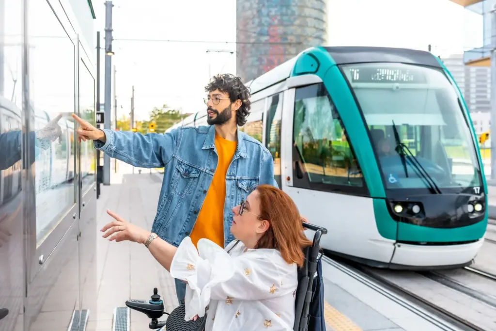 Woman in wheelchair and her male support worker at a tram stop looking at directions